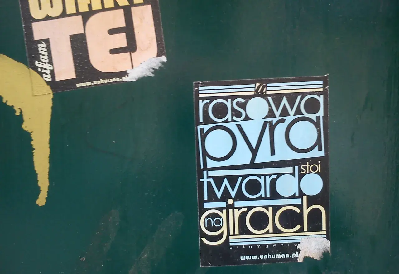 Rasowa pyra stoi twardo na girach" - to hasło w gwarze poznańskiej na czarnej naklejce.