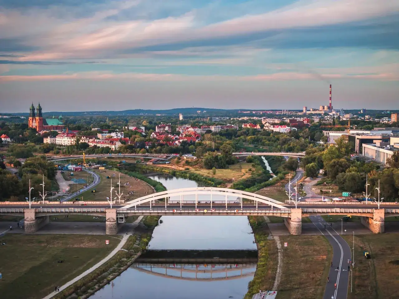 Widok na Poznań z mostami nad rzeką Wartą, katedrą i panoramą miasta w tle.
